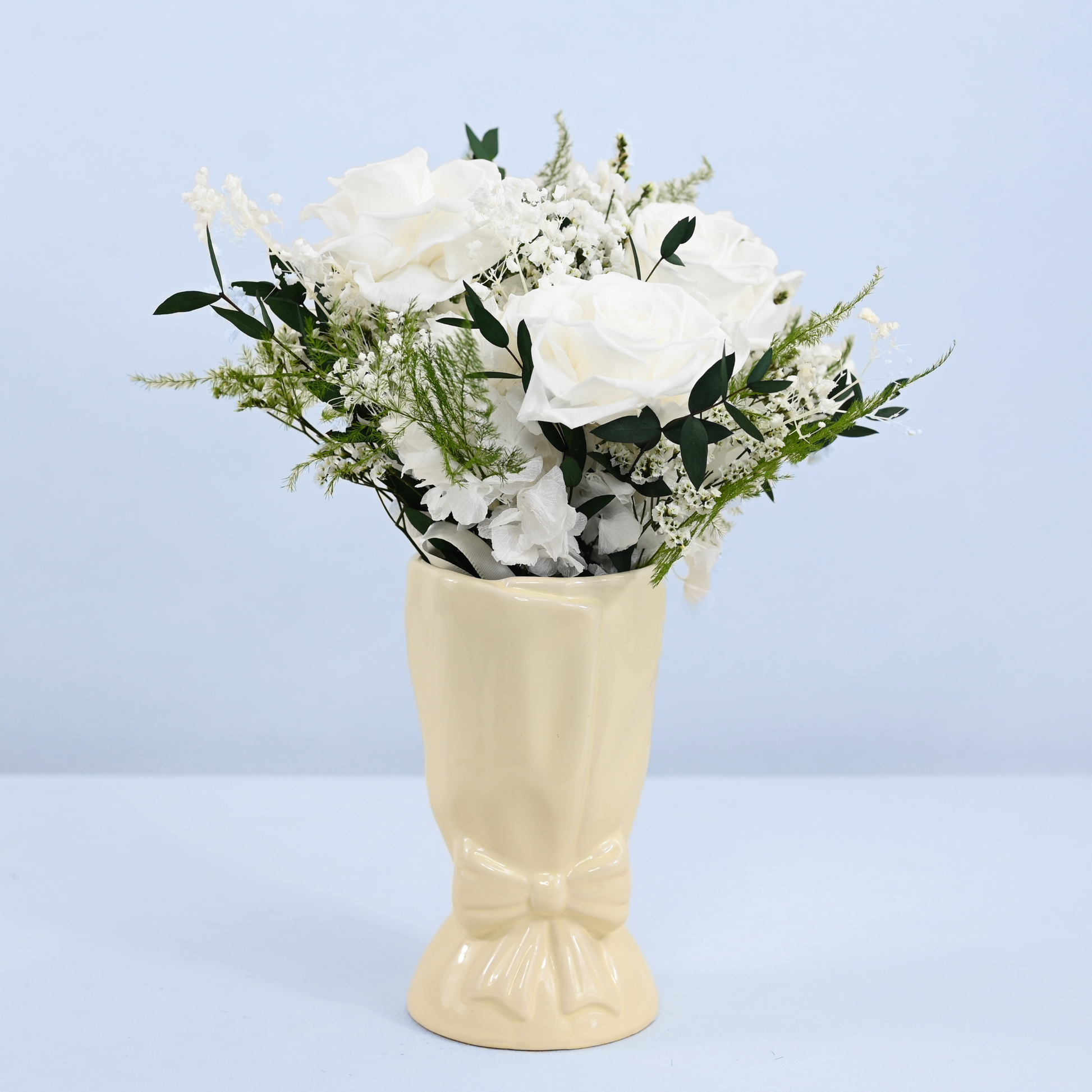 Opal Promise Petit Preserved Flower Bouquet displayed in a cream ceramic bow vase, front view