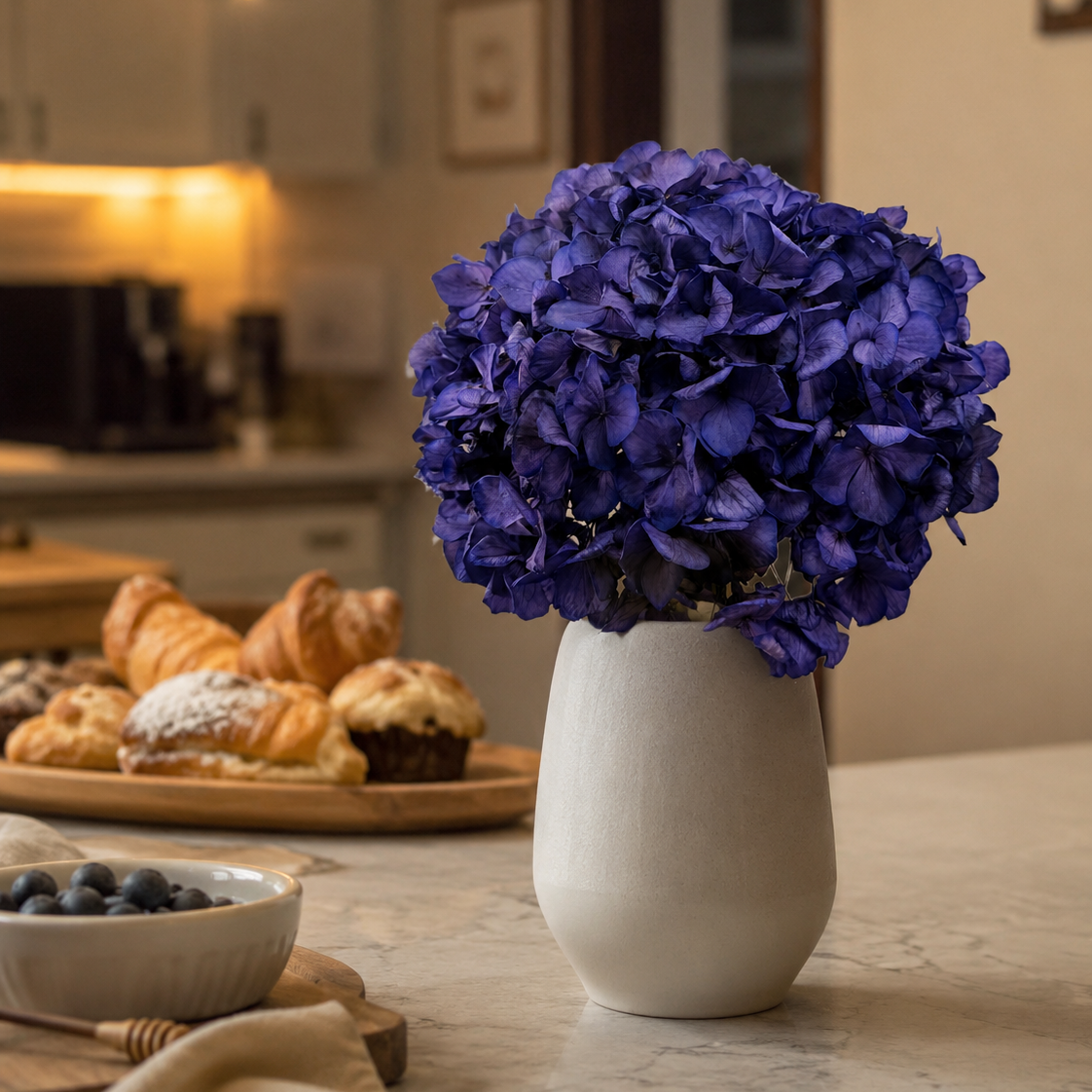 Violet preserved hydrangea stems styled in a vase on a side table