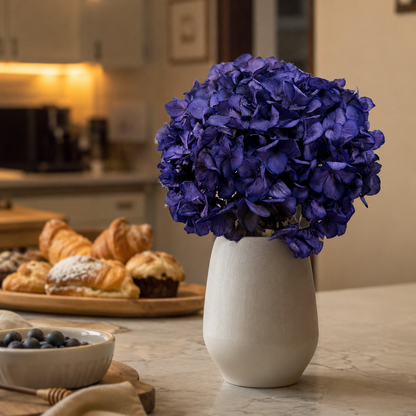 Violet preserved hydrangea stems styled in a vase on a side table