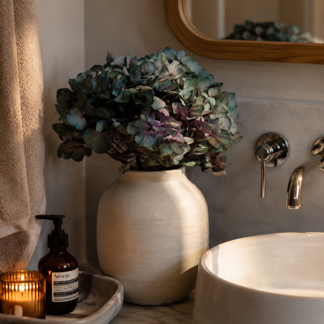 Antique green preserved hydrangea stems styled in a vase by a bathroom sink