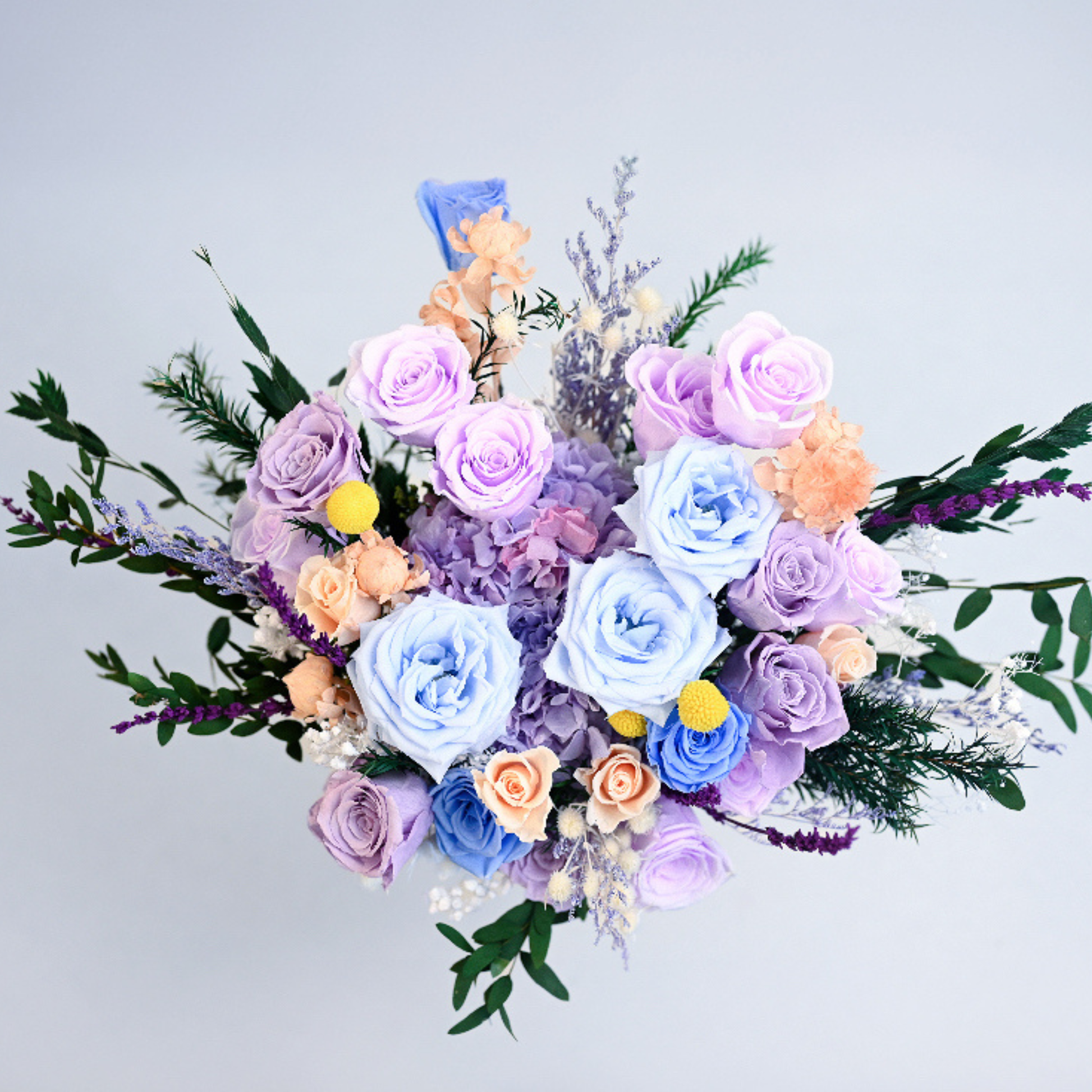 Aerial view of the Lavender Sky Preserved Flower Bouquet showing blue, lavender, and champagne roses with craspedia and lavender sprigs