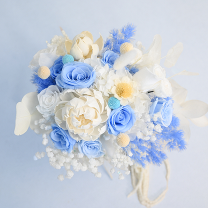 Aerial view of Sapphire Veil Preserved Flower Bouquet showing blue roses, white pith flower, craspedia, baby's breath and blue asparagus fern