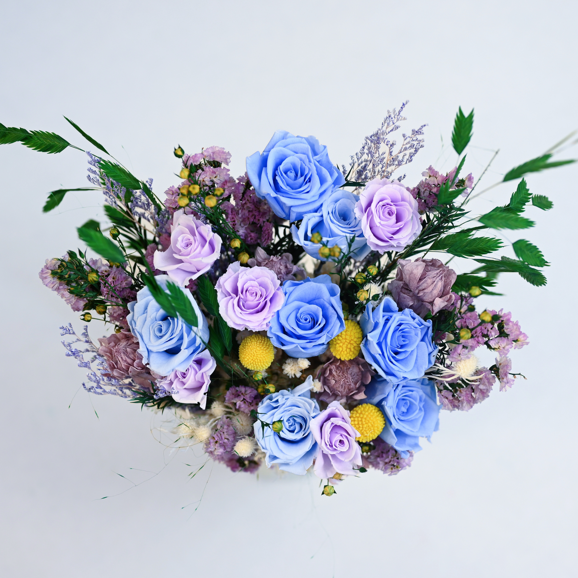 Aerial view of the Moonstone Garden Preserved Flower Bouquet showing blue and lavender roses with yellow craspedia and purple statice
