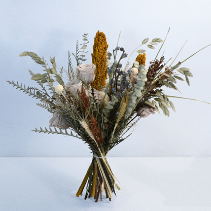 Canyon Muse Preserved Flower Bouquet featuring grey nude roses, dried sorghum, silver fern and eucalyptus with satin ribbon against a soft background