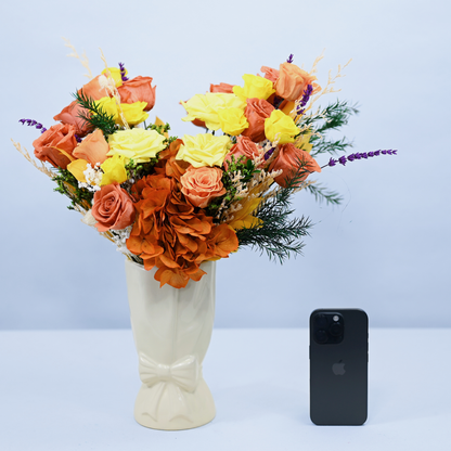 Golden Hour Preserved Flower Bouquet in cream ceramic bow vase shown next to an iPhone for size reference