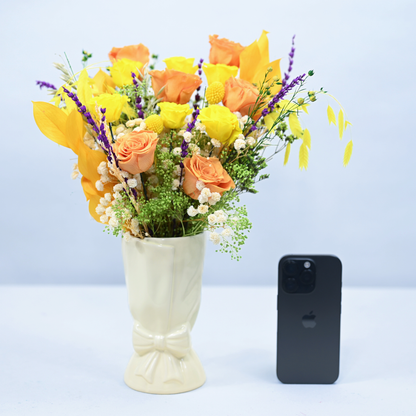 Citrus Meadow Preserved Flower Bouquet in cream ceramic bow vase shown next to an iPhone for size reference