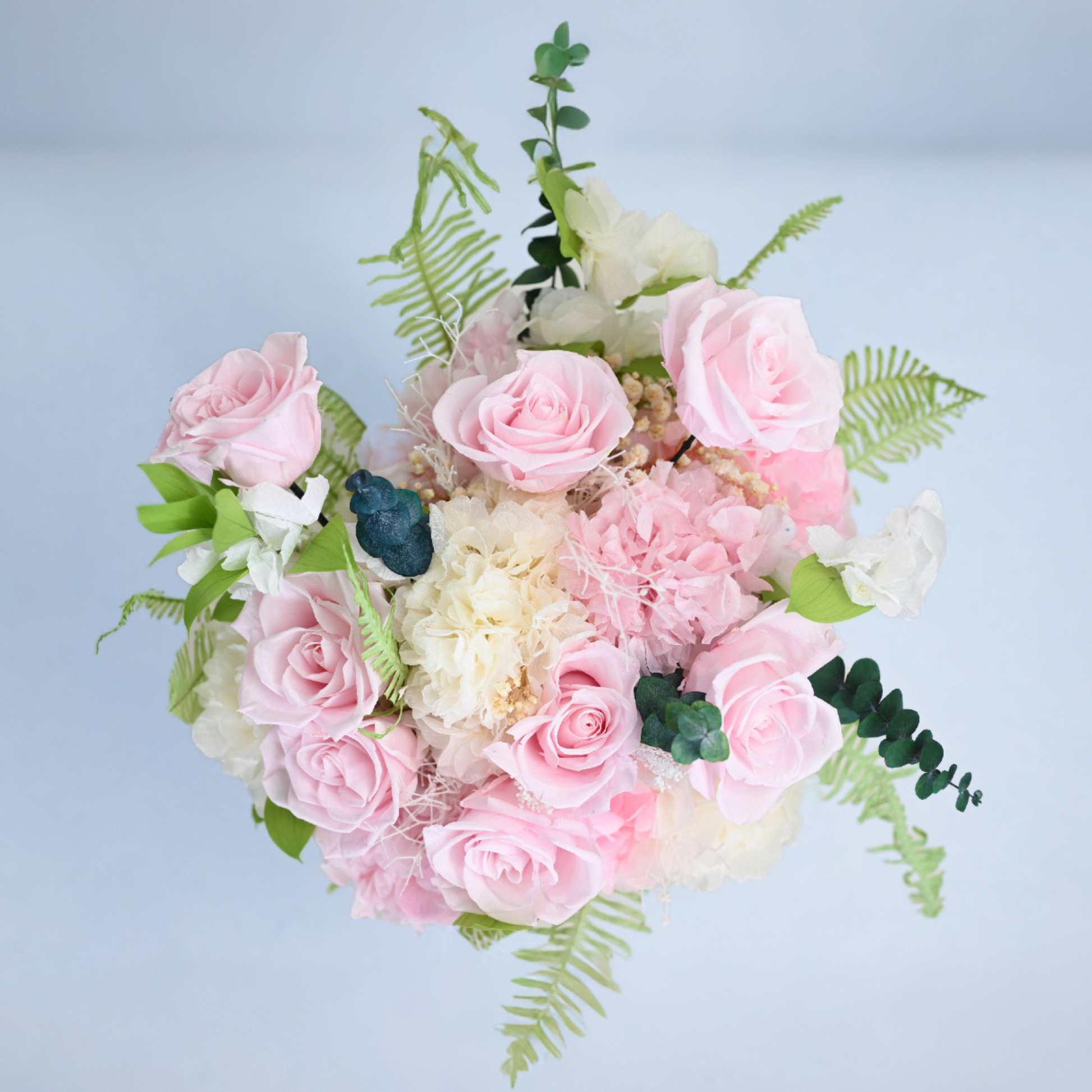 Aerial view of Rose Villa Preserved Flower Bouquet featuring pink roses, mixed carnations, eucalyptus and leatherleaf fern