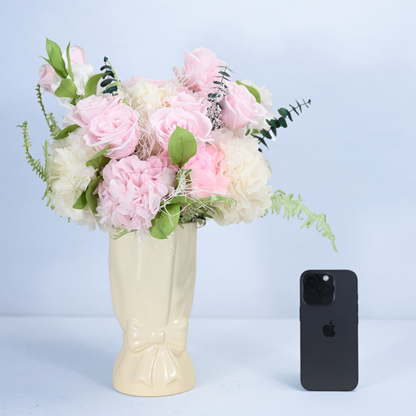 Rose Villa Preserved Flower Bouquet in cream ceramic bow vase shown next to an iPhone for size reference