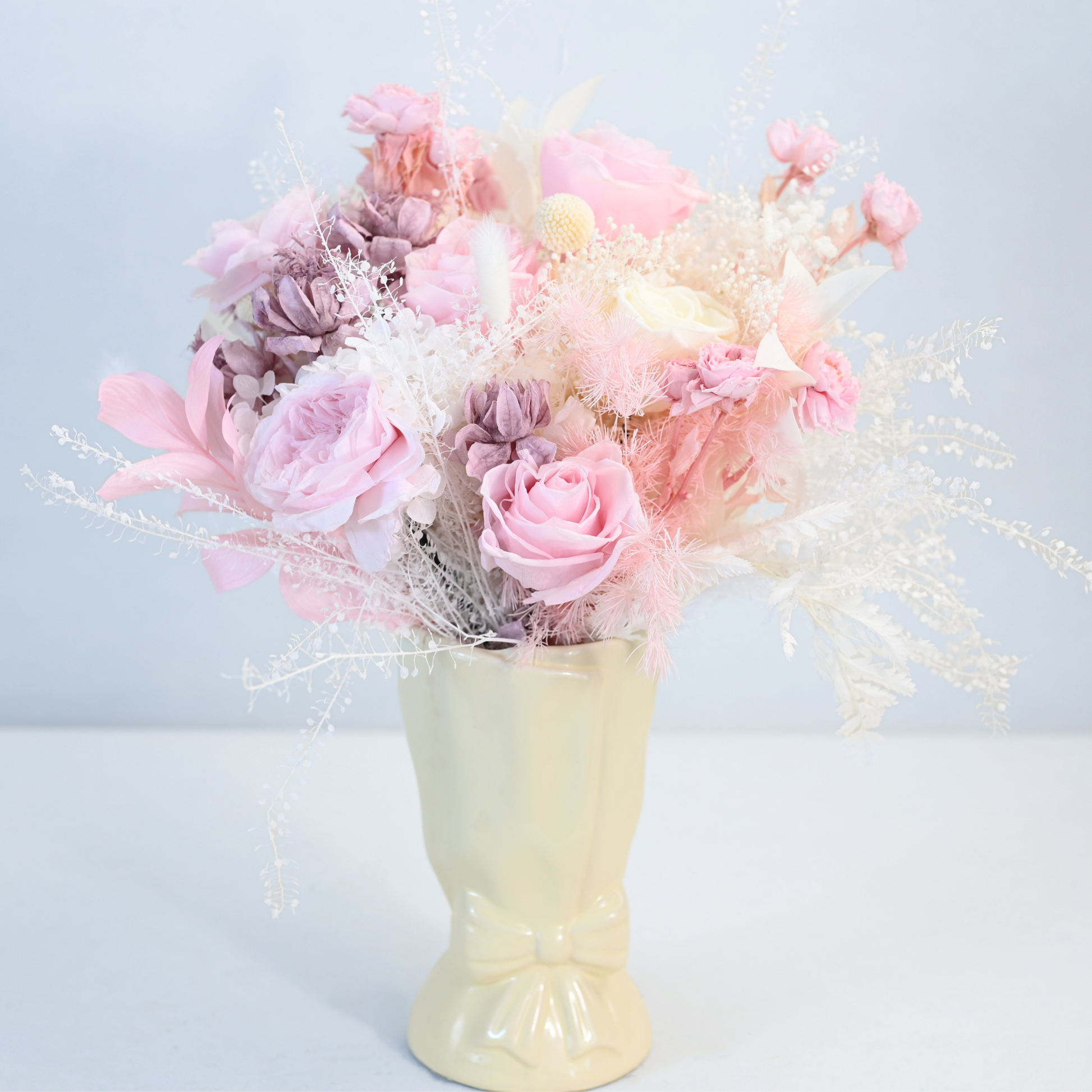 Blush Muse Preserved Flower Bouquet displayed in a cream ceramic bow vase, front view