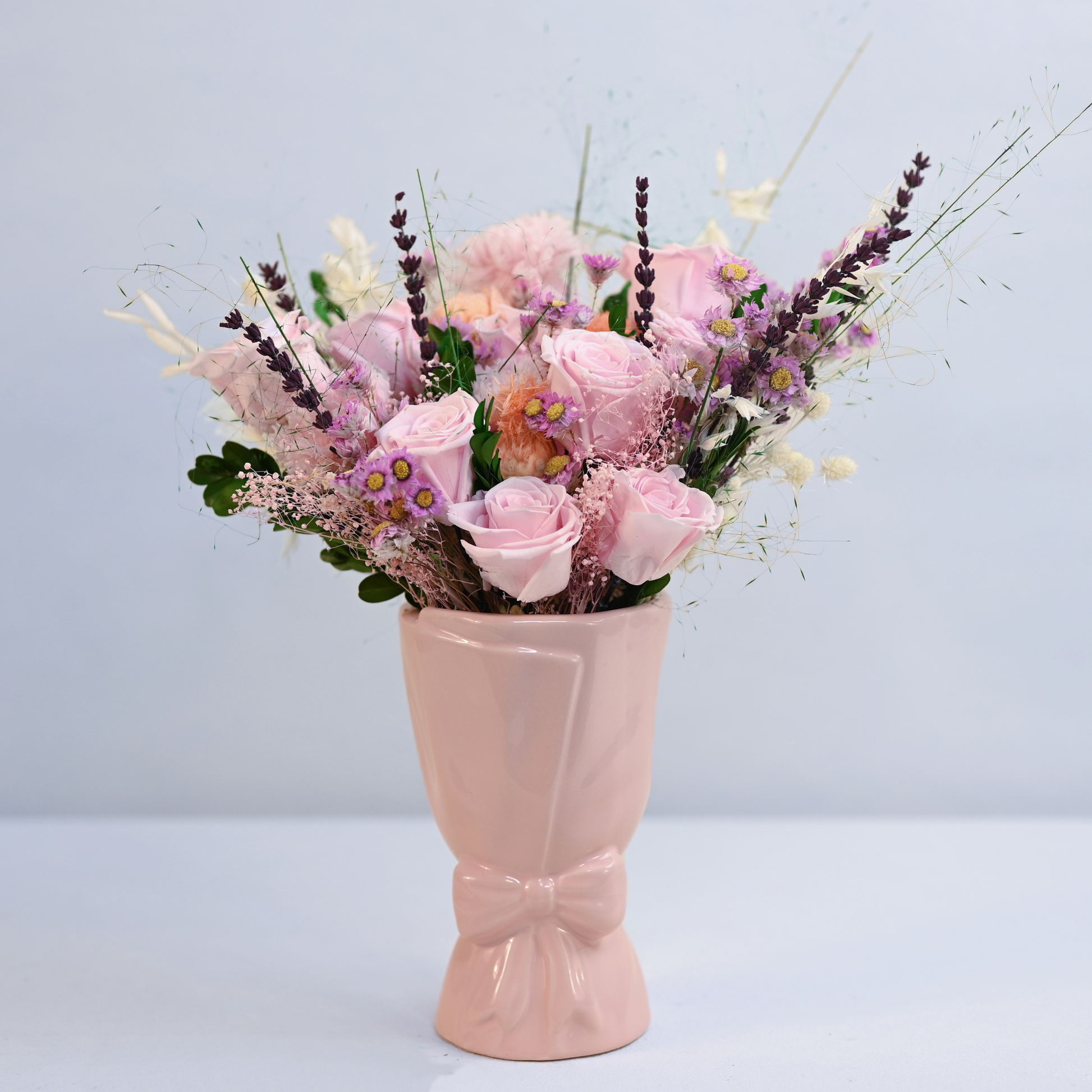 Wild Rose Preserved Flower Bouquet with pink roses, carnation, lavender, and rhodanthe displayed in a pink ceramic bow vase