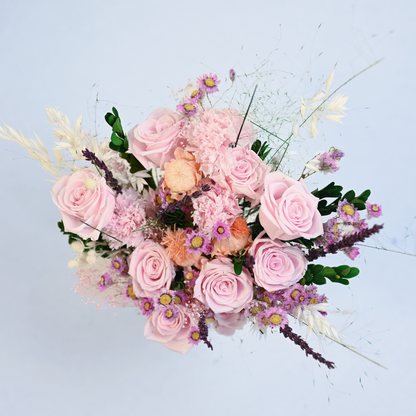 Aerial view of the Wild Rose Preserved Flower Bouquet showing pink roses, craspedia, and baby's breath arranged in a pink ceramic vase