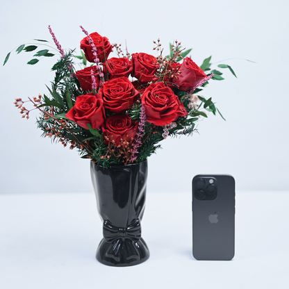 Ruby Romance Preserved Rose Bouquet in a black ceramic bow vase next to an iPhone for size reference
