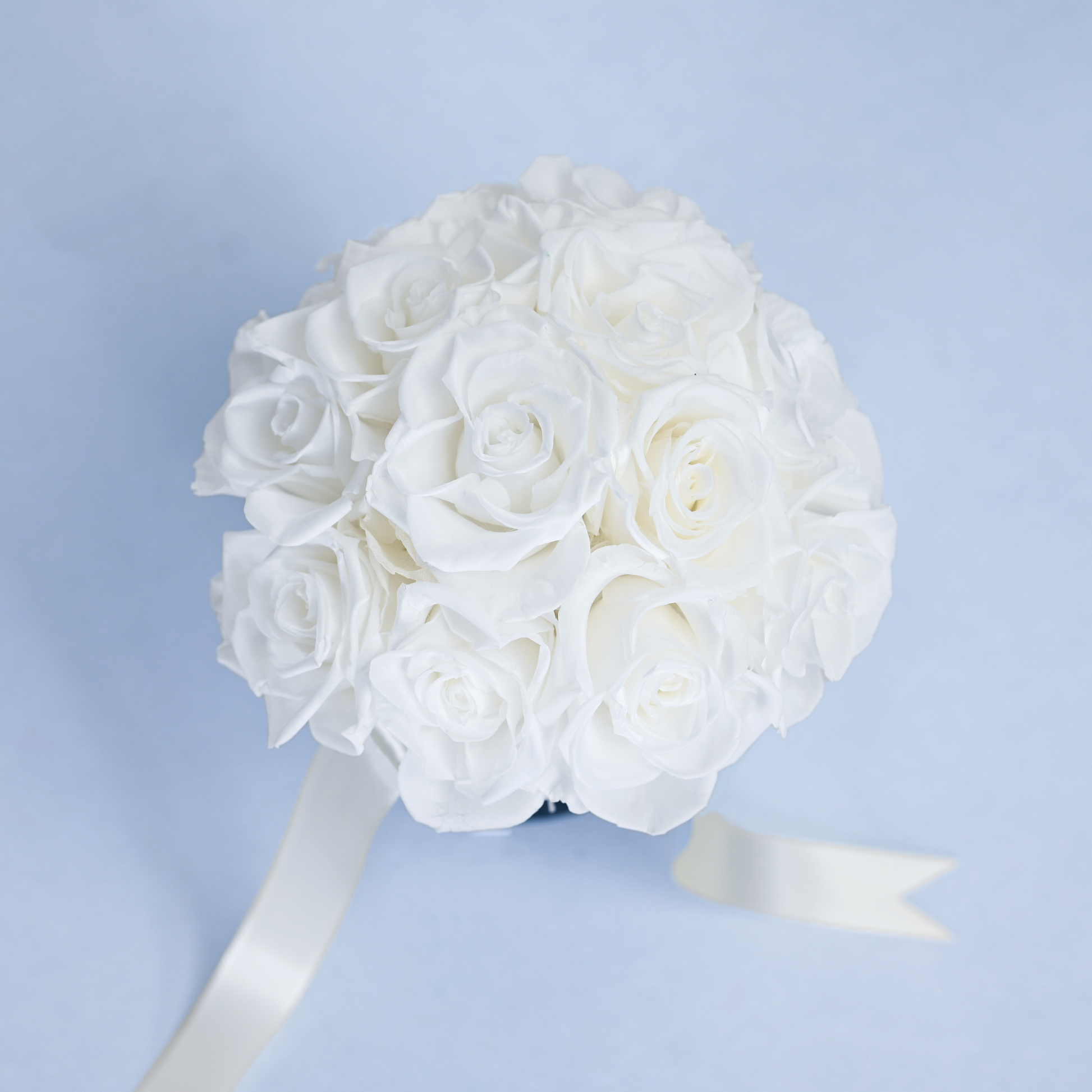 Close-up aerial view of Opal Preserved Rose Bouquet showing tightly arranged white preserved roses with cream satin ribbon