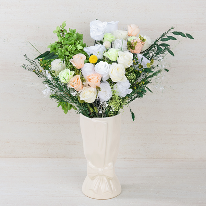 Opal Bloom Preserved Flower Bouquet with white, cream and peach roses, green hydrangea and lush mixed foliage displayed in a white ceramic bow vase, front view