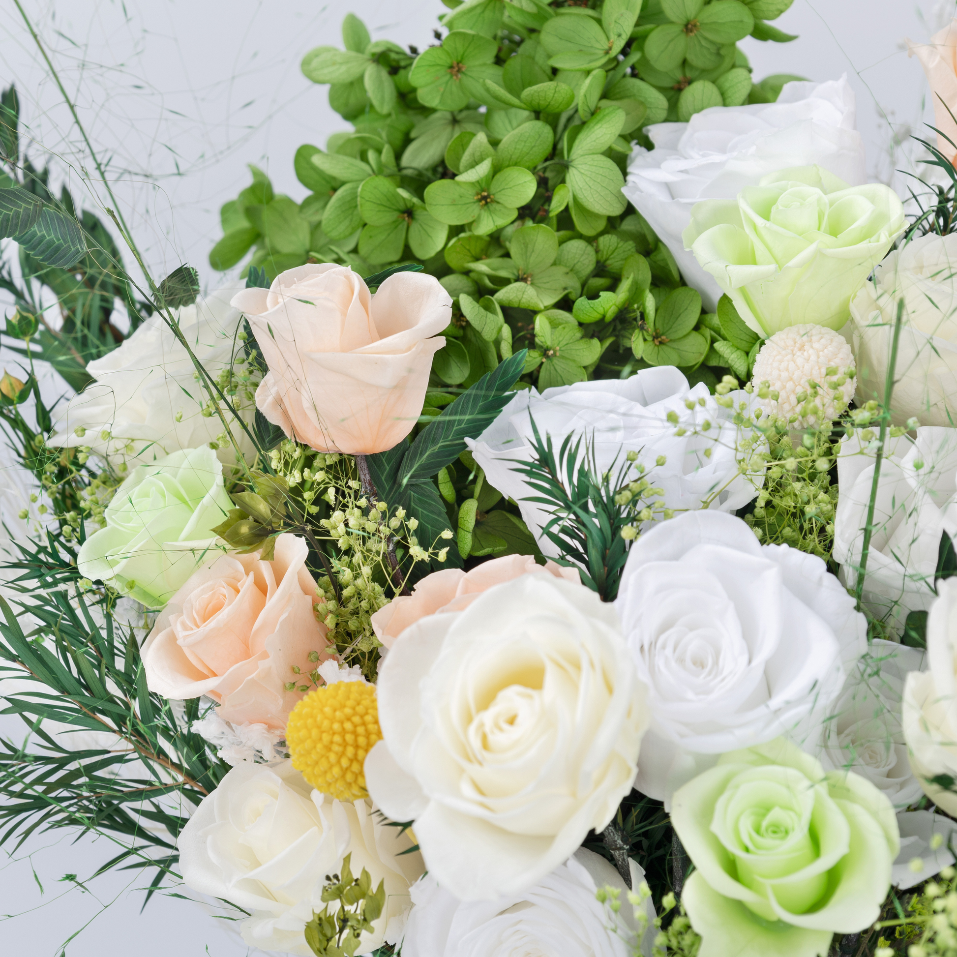 Close-up of Opal Bloom Preserved Flower Bouquet showing white, cream and apple green roses, peach roses, craspedia and green hydrangea detail