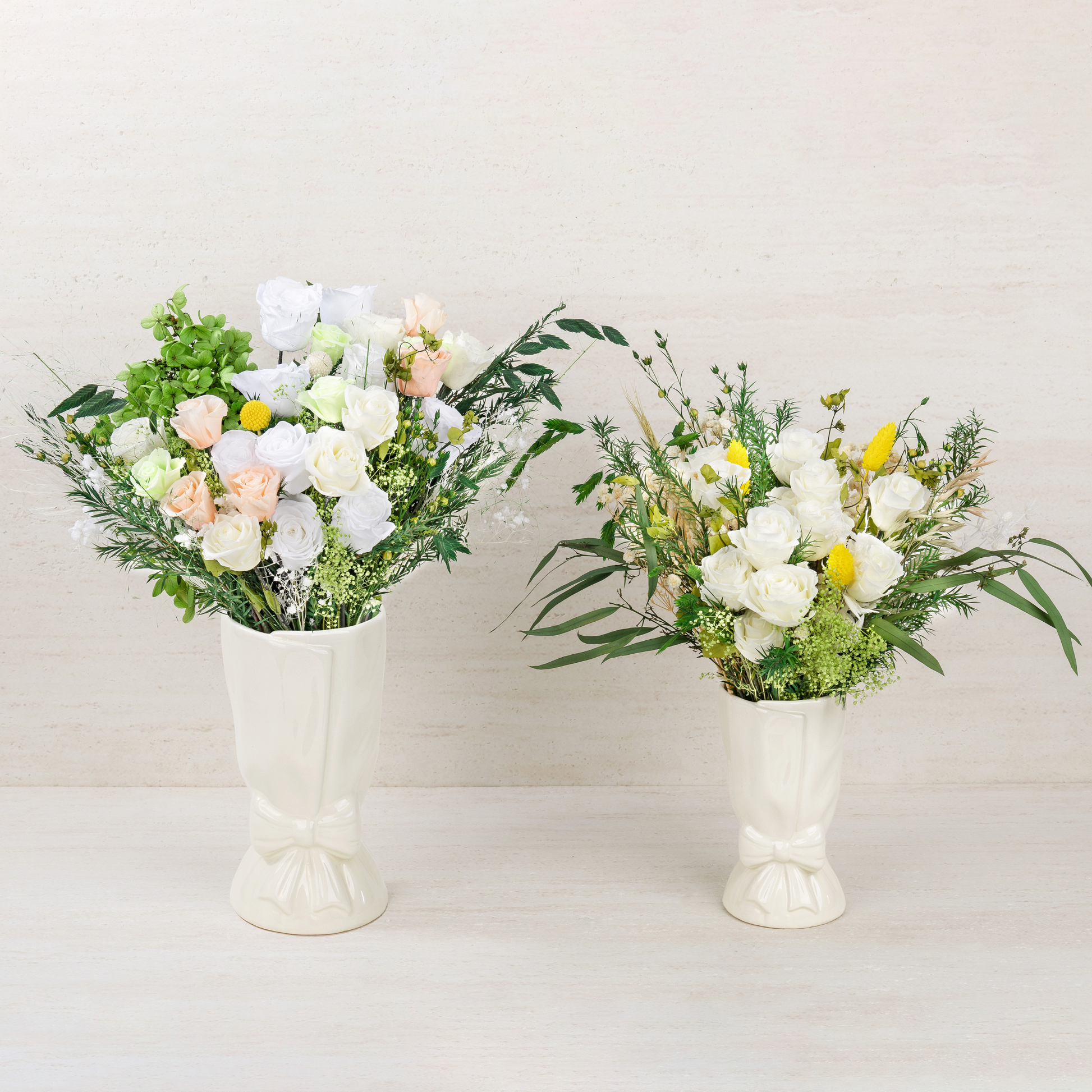 Opal Bloom and Opal Meadow Preserved Flower Bouquets displayed side by side in white ceramic bow vases, showing the difference in size and color palette