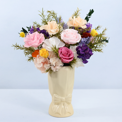 Rainbow Garden Preserved Flower Bouquet displayed in a cream ceramic bow vase, front view