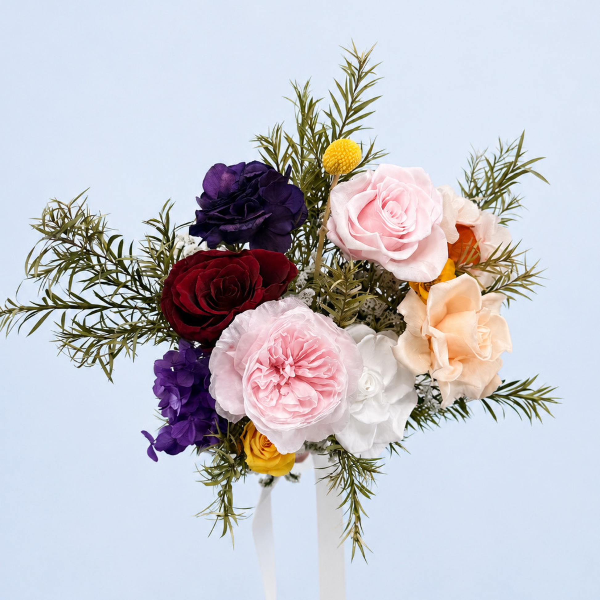 Aerial view of Rainbow Garden Petit Preserved Flower Bouquet featuring pink, peach, red and yellow roses, purple hydrangea and asparagus fern