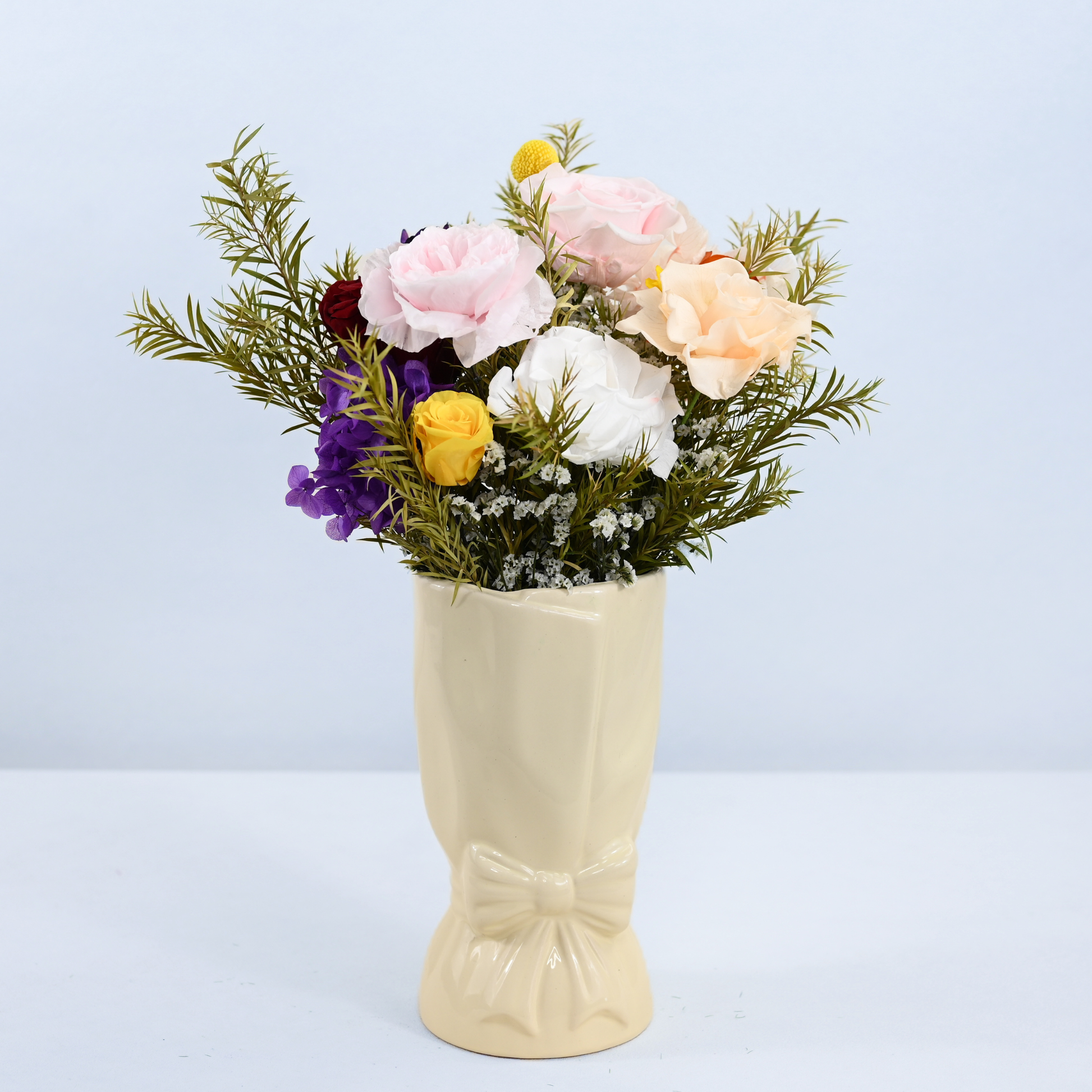 Rainbow Garden Petit Preserved Flower Bouquet displayed in a cream ceramic bow vase, front view