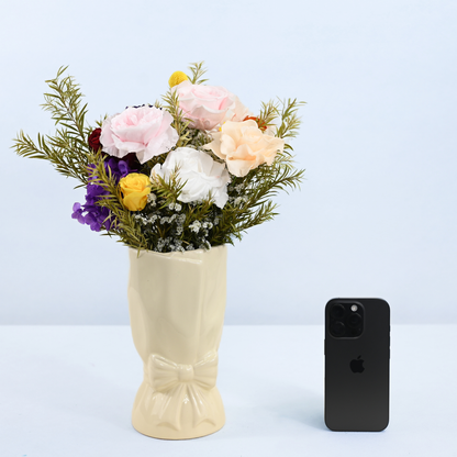 Rainbow Garden Petit Preserved Flower Bouquet in cream ceramic bow vase shown next to an iPhone for size reference